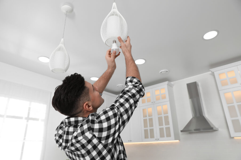 man changing a light bulb at home